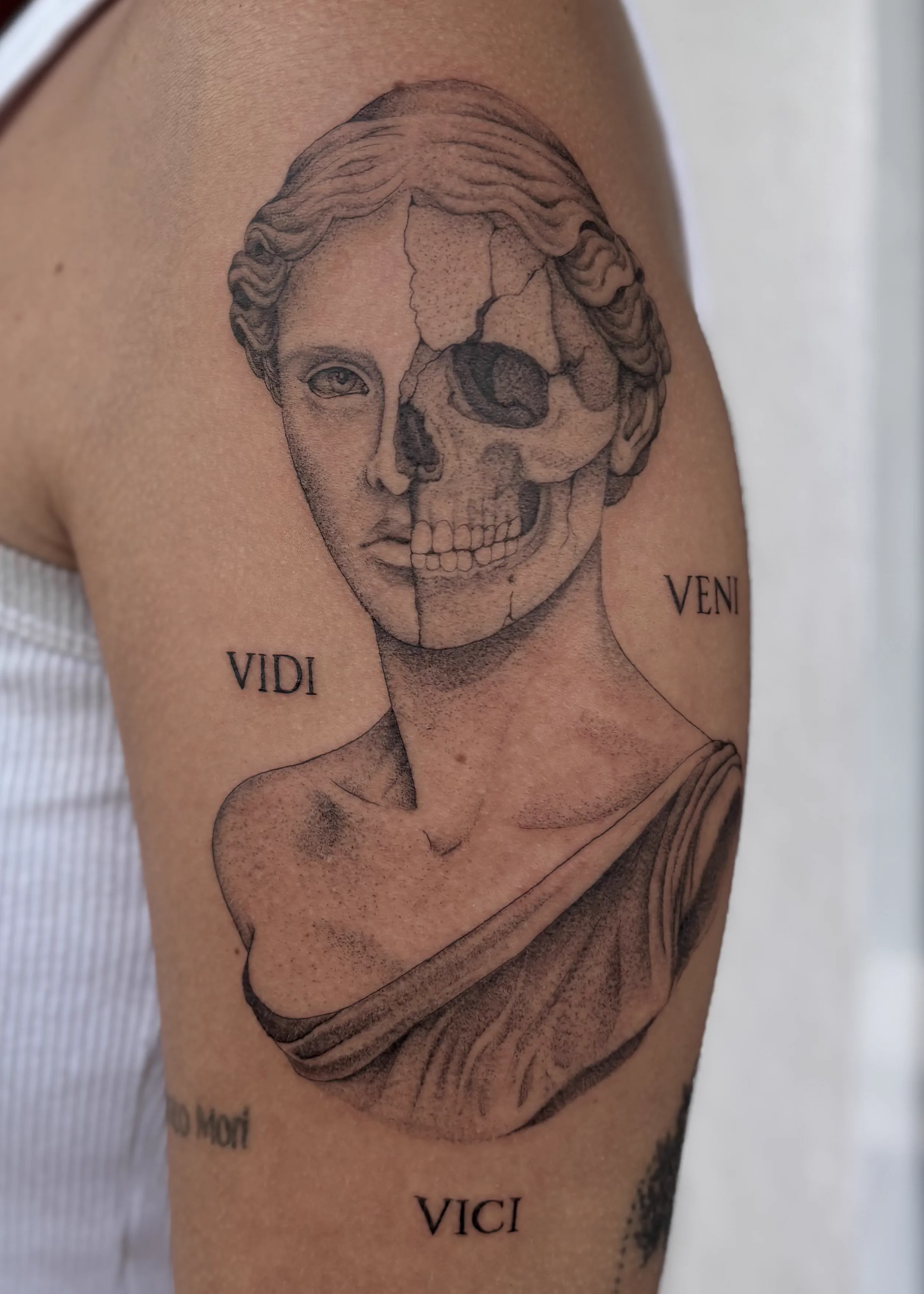 Tatuagem autoral de escultura clássica e caveira no braço
